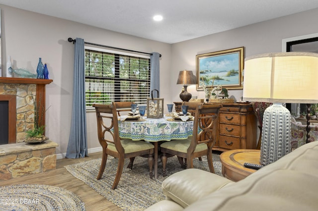 dining area with a fireplace, light hardwood / wood-style floors, and a textured ceiling