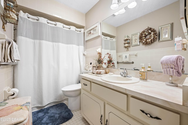 bathroom with tile patterned flooring, a textured ceiling, toilet, vanity, and tile walls