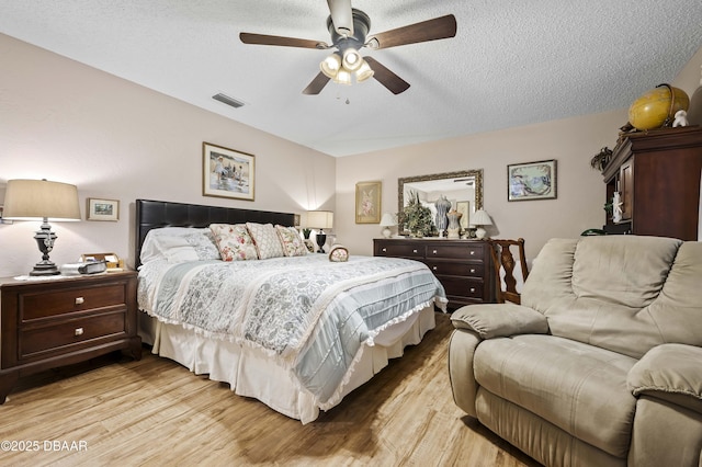 bedroom featuring ceiling fan, a textured ceiling, and light wood-type flooring