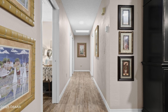 hall with a textured ceiling and light hardwood / wood-style floors