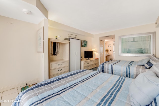 bedroom with ensuite bath and light tile patterned floors