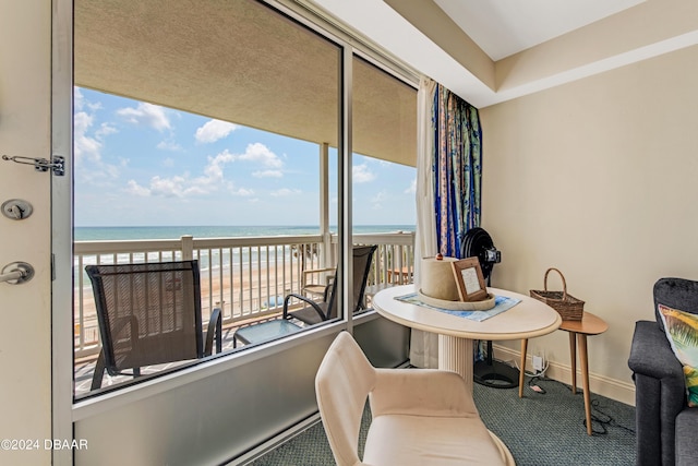 sitting room with carpet flooring, a water view, and a beach view