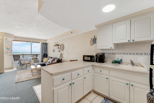 kitchen featuring kitchen peninsula, white cabinetry, sink, and light carpet