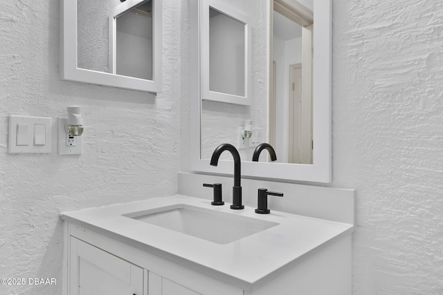 bathroom with vanity and a textured wall