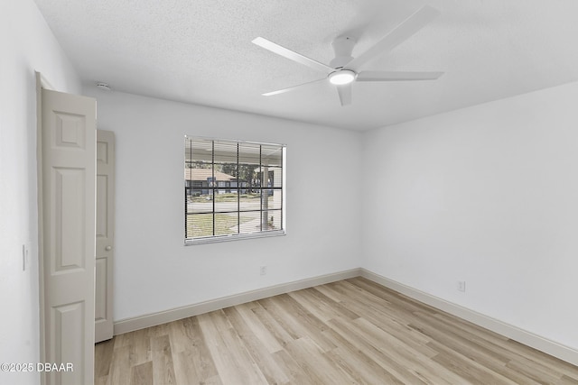 spare room with baseboards, a ceiling fan, light wood-type flooring, and a textured ceiling