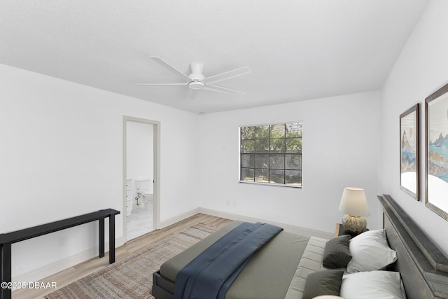 bedroom featuring light wood finished floors, a ceiling fan, ensuite bathroom, and baseboards