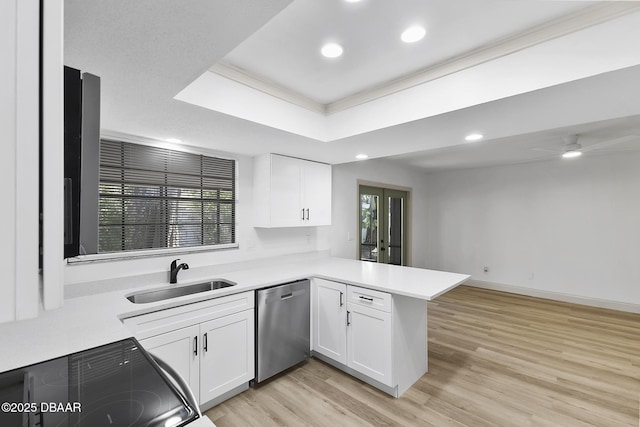 kitchen featuring a sink, stainless steel dishwasher, white cabinetry, a peninsula, and a raised ceiling