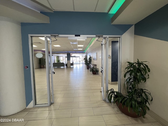 exercise room featuring light tile patterned floors and a paneled ceiling