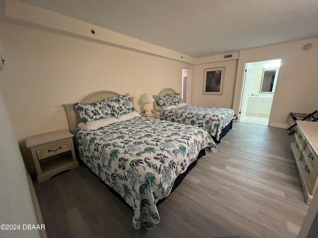 bedroom with light hardwood / wood-style floors and ensuite bath