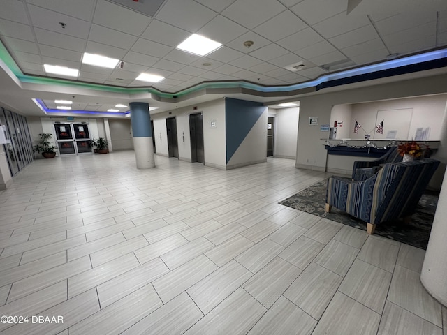 interior space featuring a paneled ceiling, elevator, and a tray ceiling