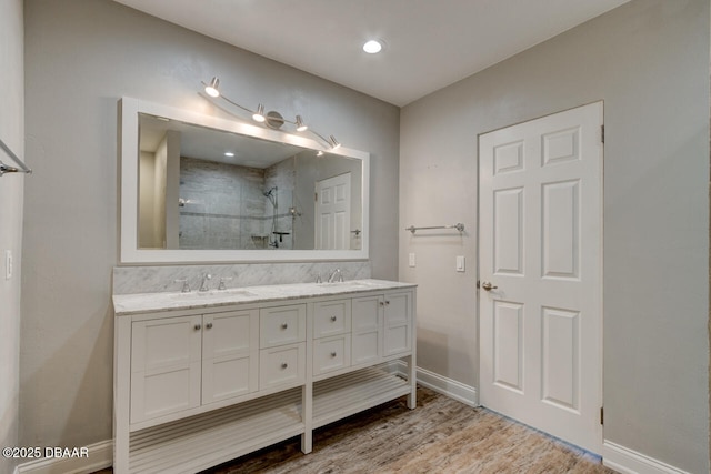 bathroom with hardwood / wood-style flooring, vanity, and tiled shower