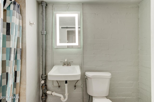 bathroom with sink, curtained shower, and toilet