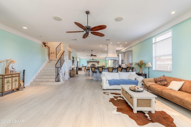 living room featuring crown molding, light hardwood / wood-style flooring, and ceiling fan