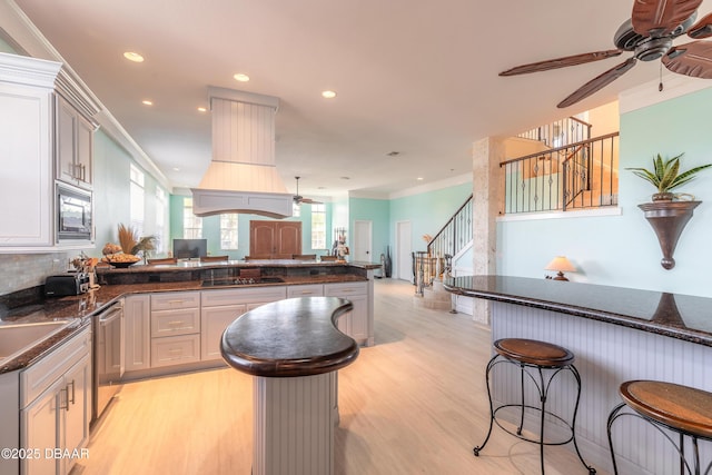 kitchen featuring dishwasher, light wood-type flooring, ornamental molding, kitchen peninsula, and a breakfast bar area