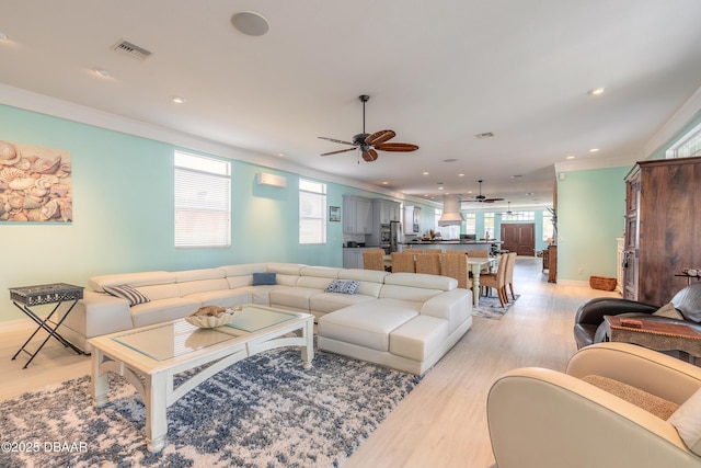 living room featuring a wall unit AC, ceiling fan, light hardwood / wood-style flooring, and ornamental molding