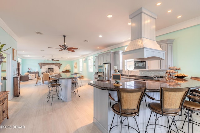 kitchen with a kitchen breakfast bar, ceiling fan, decorative backsplash, stainless steel fridge with ice dispenser, and black microwave