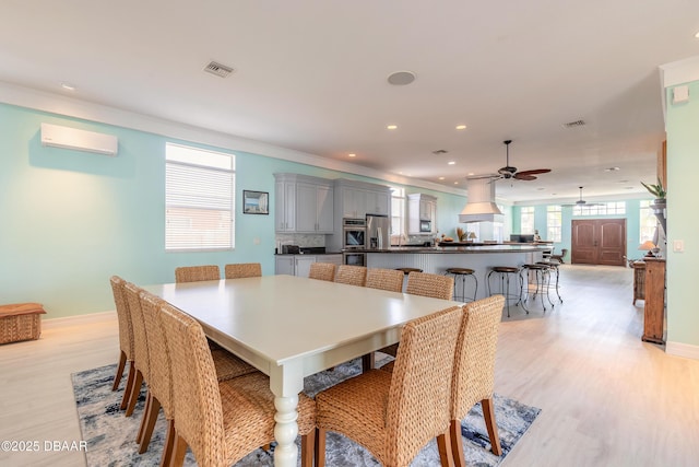 dining room with light hardwood / wood-style flooring, a wall unit AC, ceiling fan, and crown molding