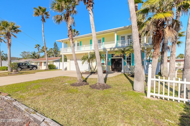 view of front of property featuring a front yard, a balcony, and a garage