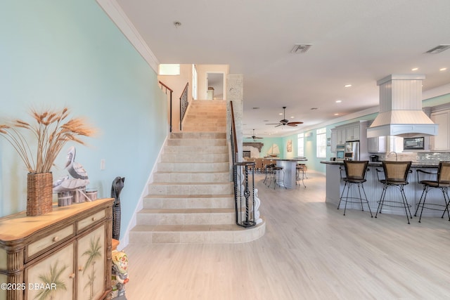 staircase featuring hardwood / wood-style floors, ceiling fan, and ornamental molding