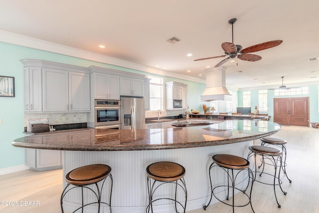 kitchen featuring a breakfast bar, sink, stainless steel appliances, and custom exhaust hood