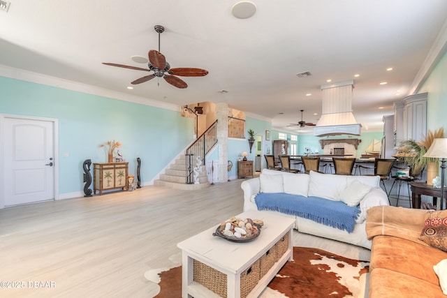 living room featuring light hardwood / wood-style floors, ceiling fan, and crown molding