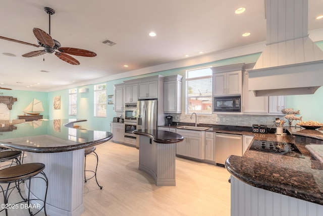 kitchen featuring ceiling fan, sink, black appliances, a center island, and light hardwood / wood-style floors