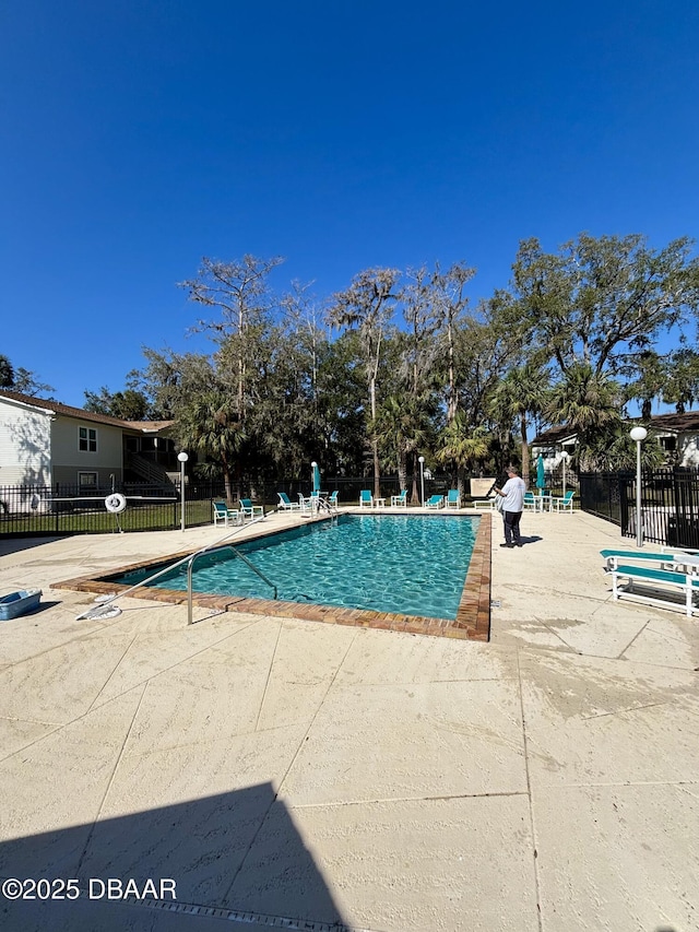 pool with a patio area and fence