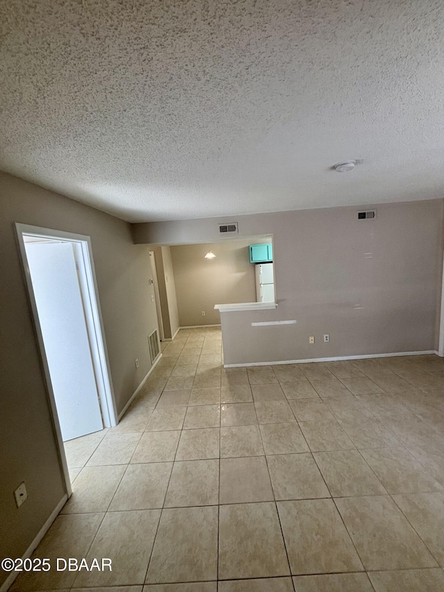 empty room featuring light tile patterned floors, a textured ceiling, and visible vents