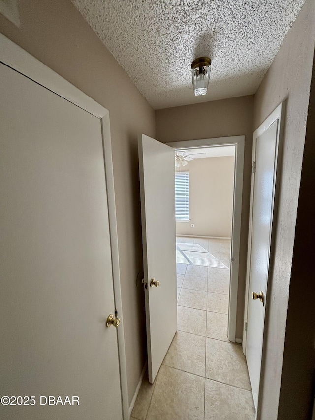 hall featuring a textured ceiling and light tile patterned flooring