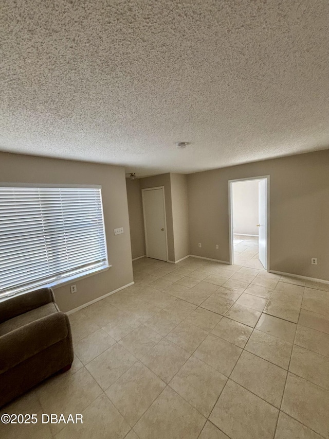 unfurnished living room with light tile patterned floors, baseboards, and a textured ceiling