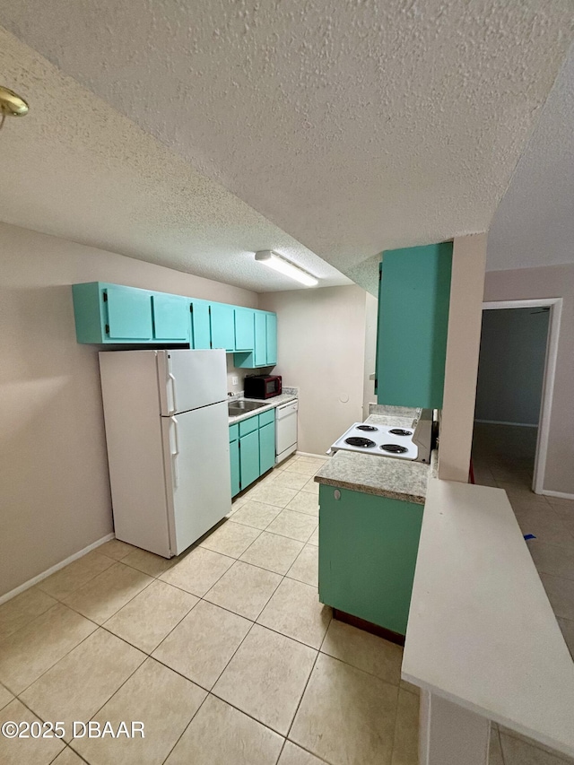 kitchen featuring light tile patterned floors, blue cabinets, light countertops, range, and freestanding refrigerator