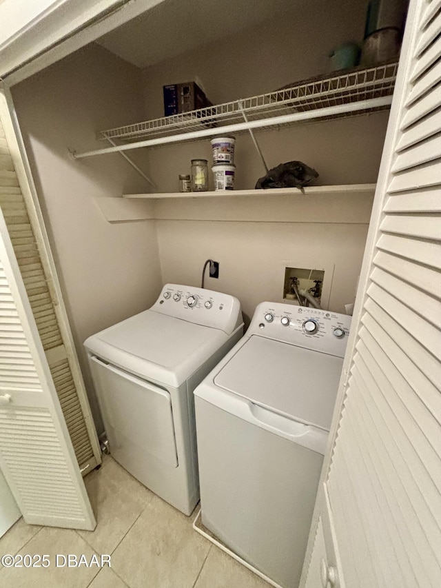 washroom featuring laundry area, washer and dryer, and light tile patterned flooring