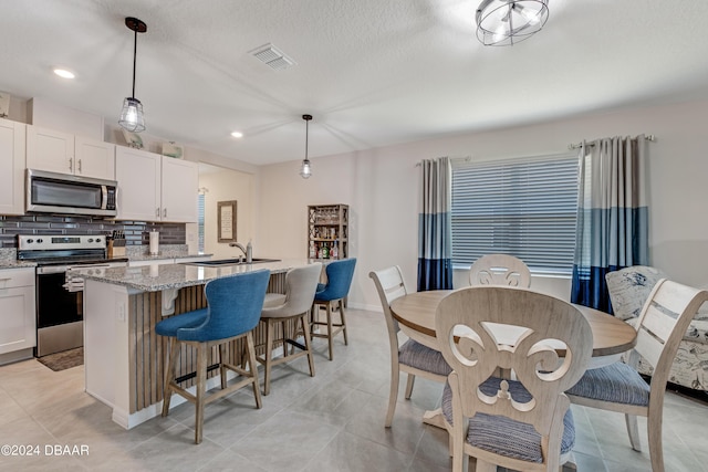 1362 Cork Dr, Ormond Beach, FL 32174 - kitchen featuring stainless steel appliances, a sink, a center island with sink, backsplash, and light stone counters