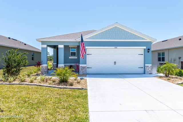 1362 Cork Dr, Ormond Beach, FL 32174 - view of front facade featuring a garage, concrete driveway, stone siding, and a front yard