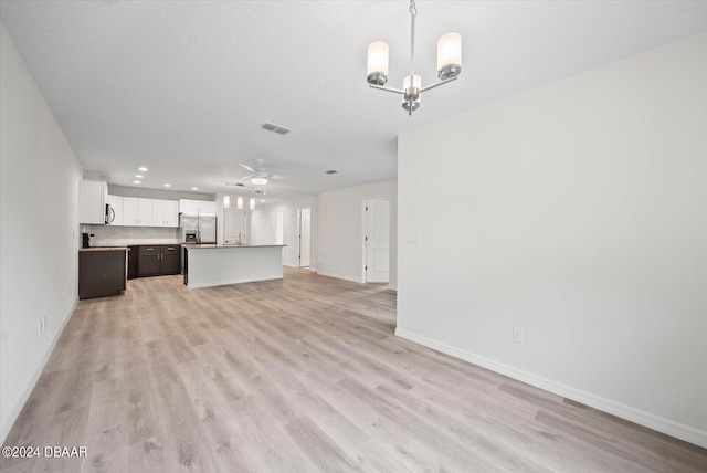 unfurnished living room featuring light wood-type flooring and ceiling fan with notable chandelier