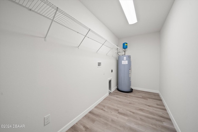 clothes washing area featuring water heater, washer hookup, light hardwood / wood-style floors, and electric dryer hookup