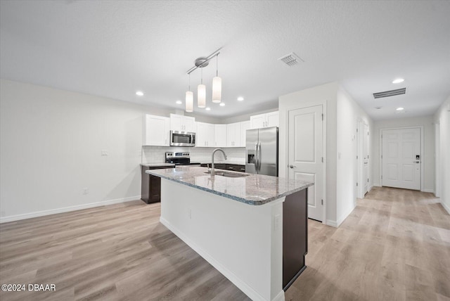 kitchen with a kitchen island with sink, white cabinetry, sink, and stainless steel appliances