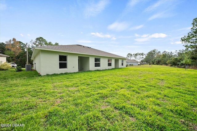 back of property featuring a lawn and central air condition unit