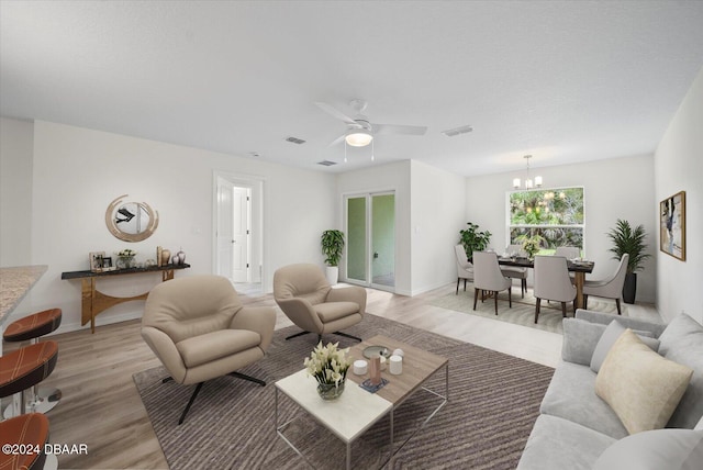 living room with light wood-type flooring and ceiling fan with notable chandelier