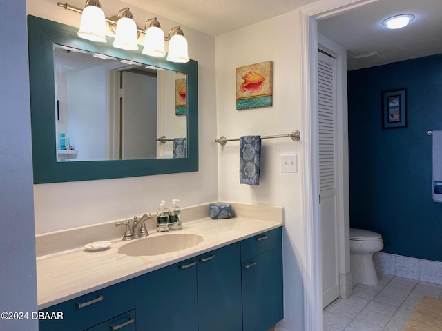 bathroom featuring baseboards, toilet, tile patterned flooring, vanity, and a closet