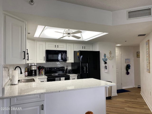 kitchen featuring black appliances, a peninsula, visible vents, and white cabinets