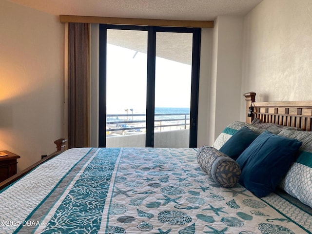 bedroom featuring a textured ceiling, a water view, and access to exterior