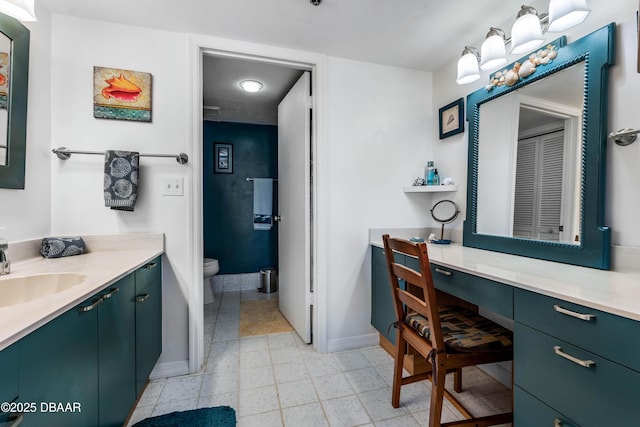 bathroom with a closet, vanity, toilet, and baseboards