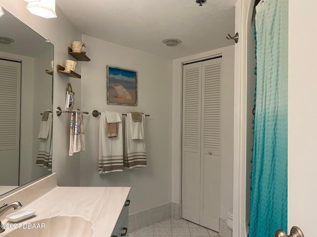 full bath featuring toilet, baseboards, a closet, and vanity