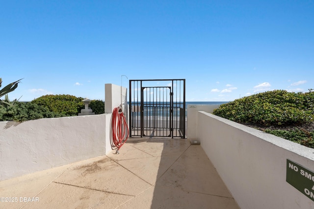 view of patio featuring a gate and a water view