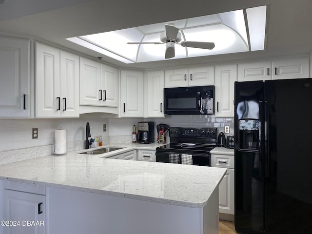 kitchen with white cabinets, a sink, a peninsula, and black appliances