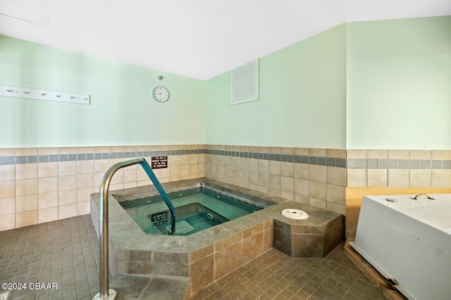 bathroom featuring a garden tub, tile walls, and tile patterned floors