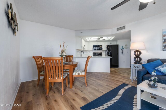 living room featuring hardwood / wood-style floors, ceiling fan, and a textured ceiling