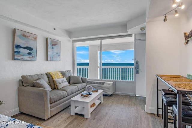 living room with a water view, light wood-type flooring, and an AC wall unit