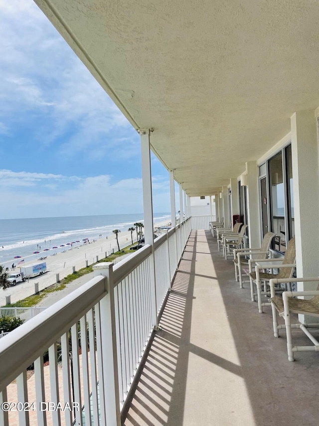 balcony featuring a view of the beach and a water view